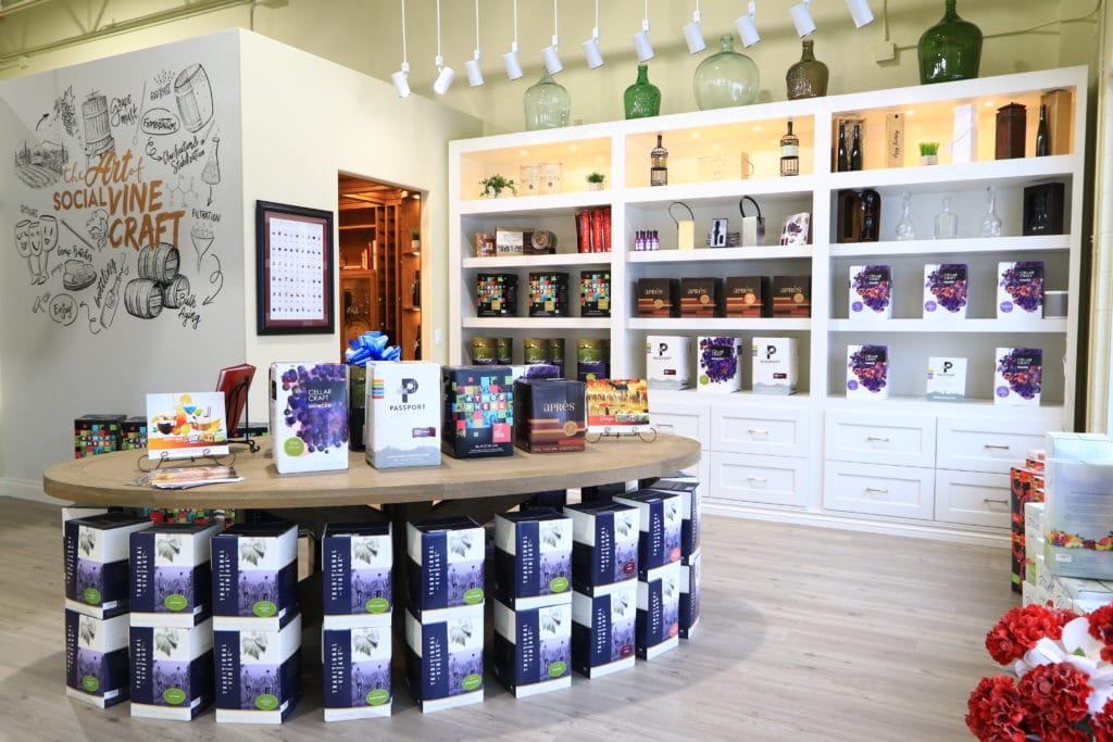 Interior of The Vint Haus store. Center table wine kit display with wine cellar and kits in background